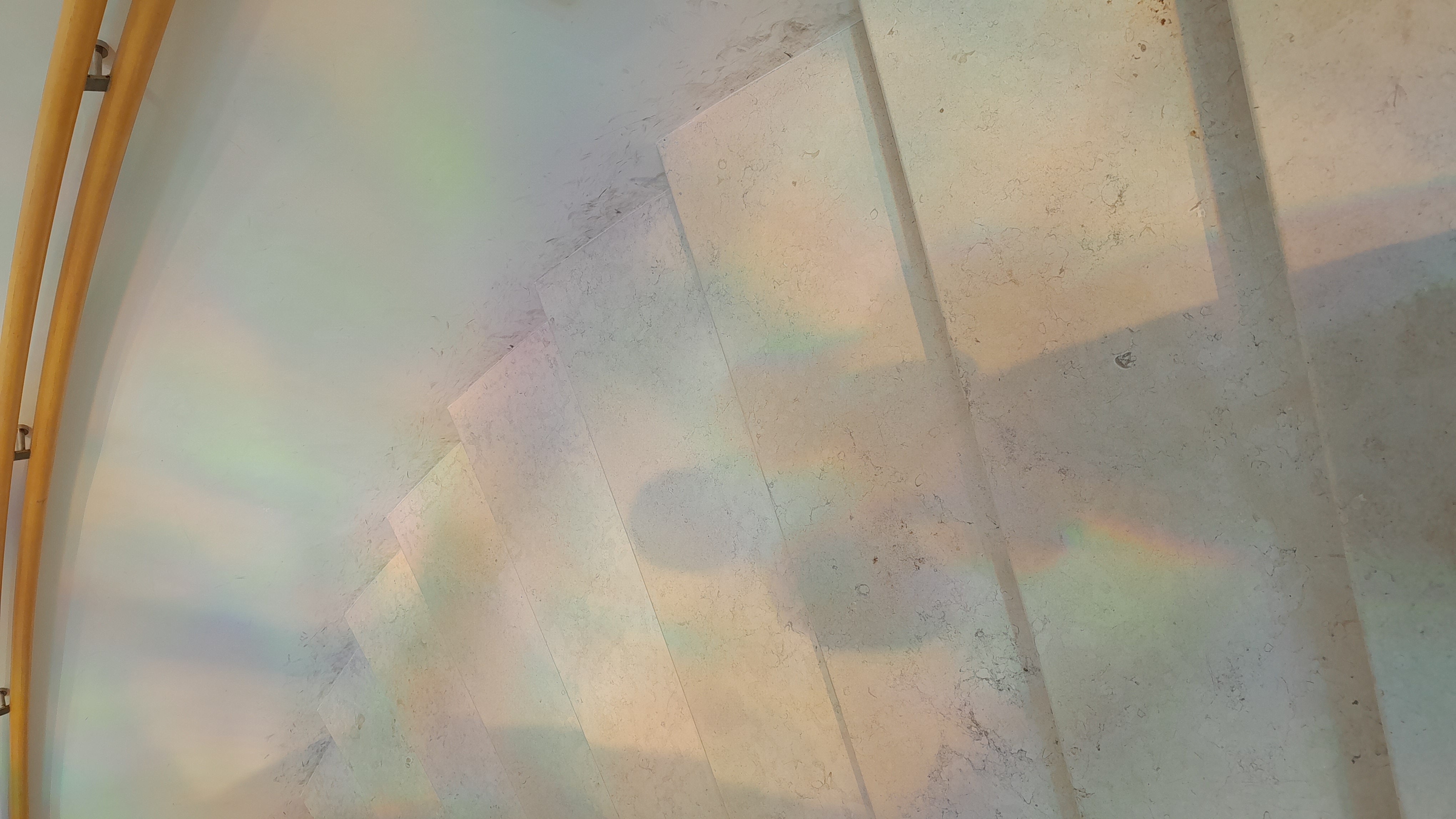Prismatic rainbow light cast across pale stone stairs